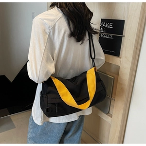 Close-up of black nylon crossbody bag with contrasting vibrant yellow woven shoulder strap
