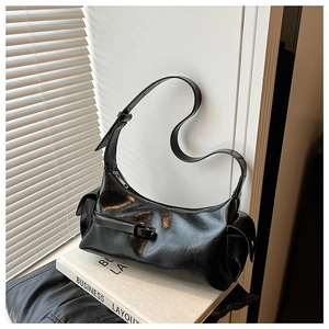 Close-up of black glossy crescent bag featuring silver zippers and stylish side pockets