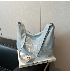 Détail du sac demi-lune en denim bleu clair avec imprimés de dessins animés et lettres blancs