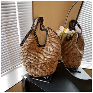 Detailed close-up of handmade straw woven hobo bag with black contrast crochet edge