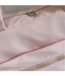 Detail view of pink fabric texture and smooth dual metal zippers on travel bag