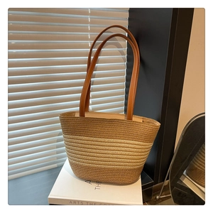 Detail view showing the gradient woven straw texture and premium brown leather handles