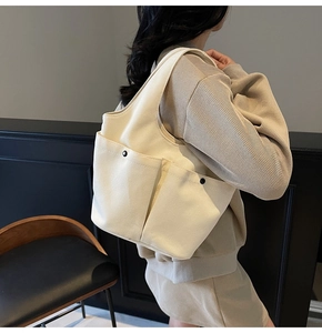 Close-up of cream canvas tote bag featuring pleated double pockets and black buttons