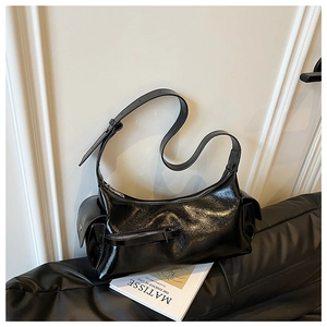 Detail of black glossy faux leather shoulder bag featuring side pockets and crackle texture