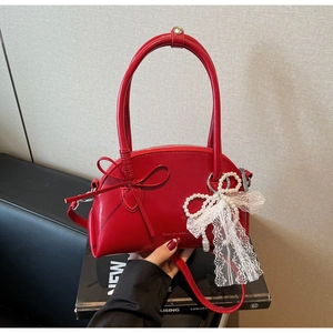Dettaglio borsa rossa lucida con ciondolo in pizzo e perle e logo stampato