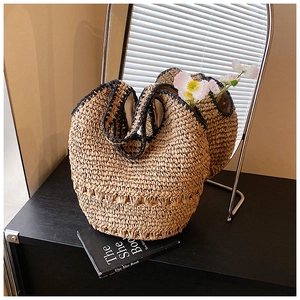 Detailed close-up of woven straw handbag texture with black contrast stitching detail