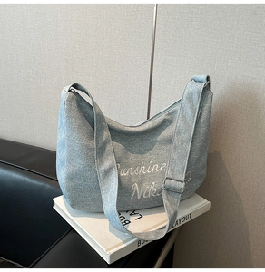Gros plan détaillé du sac cabas en toile bleue avec broderie et large bandoulière réglable