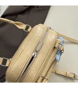 Close-up of beige boston bag with pleated leather texture and blue plaid ribbon detail