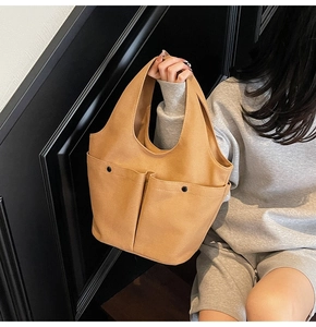 Detail of khaki canvas tote bag featuring double front pockets with black snap closures