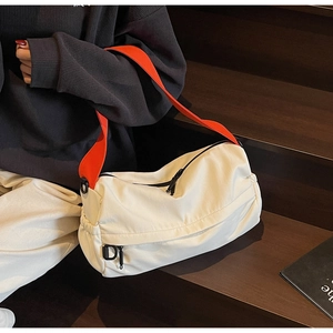 Detail of off-white nylon pillow bag with contrast orange strap and drawstring side