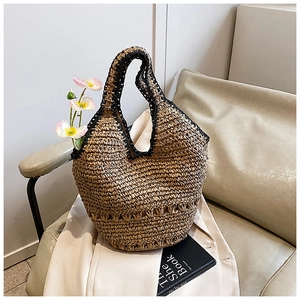 Detail of handmade woven straw hobo bag with black crochet trim on a cream blazer