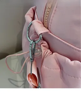 Close-up of pink travel bag showing silver metal spring hook and woven shoulder strap
