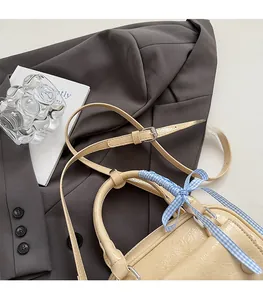 Detail of cream crossbody bag with wrinkled texture and blue checkered ribbon handle
