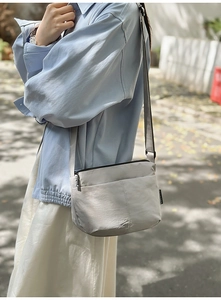 Détail du sac bandoulière en nylon gris clair résistant à l'eau avec étiquette Chummy
