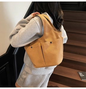 Detail of caramel canvas tote bag showing pleated pockets and shoulder carry style