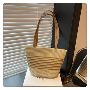 Close-up of woven straw tote bag with striped pattern and brown leather straps