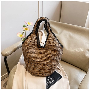 Detailed shot of handmade straw bag with black woven trim and hollow weave pattern