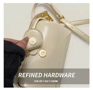 Détail du fermoir magnétique doré sur le sac Boston minimaliste en cuir crème