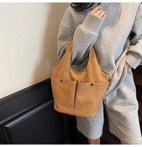 Detail view of khaki pleated tote bag featuring large front pockets and black button accents