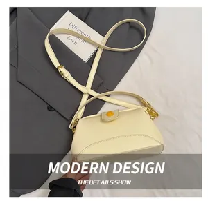 Détail du sac bandoulière trapèze blanc crème avec boucle jaune sur un costume gris
