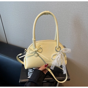 Dettaglio della borsa a mano giallo chiaro con fiocco e ciondolo di perle sul divano