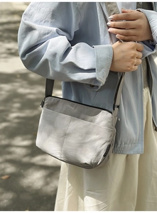 Gros plan du sac bandoulière gris clair en nylon avec bandoulière réglable et poche