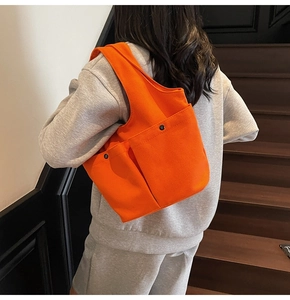 Detail of orange pleated canvas tote bag with functional double front pockets and metal snaps