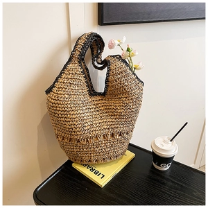 Detail of handmade straw tote bag with black woven edges and hollow flower pattern