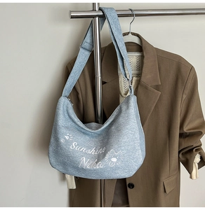Détail du sac cabas en tricot bleu clair avec texte Sunshine Nika et dessin de lion