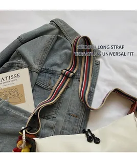 Detail of adjustable red and blue striped wide strap on white crossbody bag over denim