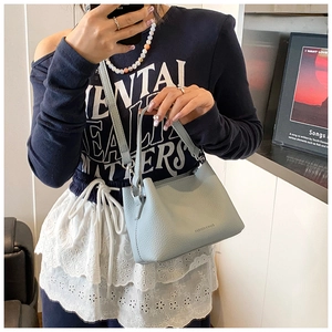 Détail du sac à bandoulière en cuir bleu clair avec motif litchi et coutures soignées