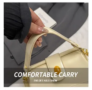 Vue détaillée d'un sac à main en cuir crème avec finitions dorées et détail en ambre
