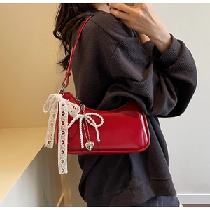 Dettaglio della borsa hobo in vernice rossa con fiocco di perle e nastro di pizzo