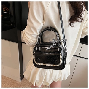 Detail of black glossy leather bag with white lace trim and checkered bow ribbon