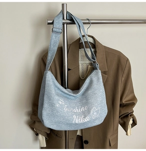 Détail du sac hobo en denim bleu clair avec imprimé animal blanc et bandoulière réglable
