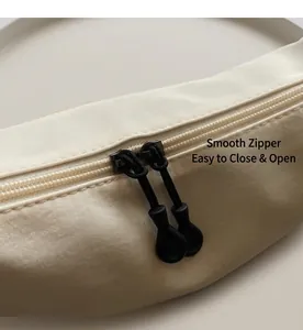 Detailed close-up of the smooth black dual zipper on a cream white nylon crossbody bag