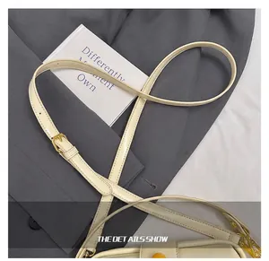 Détail de la bandoulière réglable en cuir beige avec boucle en métal doré élégante
