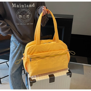 Detail of yellow nylon travel bag with quilted pocket on white rolling luggage