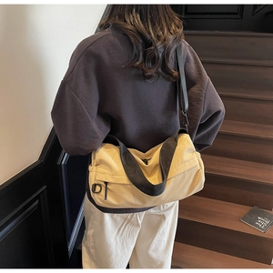 Close-up of large canvas shoulder bag featuring yellow and black contrast and side zipper