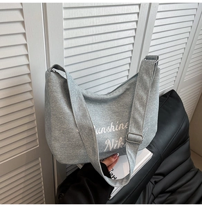 Détail du sac croissant en toile grise avec broderie blanche et boucle réglable argent