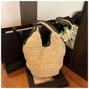 Detail of a handmade straw tote bag featuring beige weave and black contrast edges