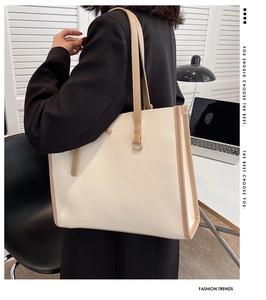 Detail of white leather tote bag with khaki straps shown in a modern office setting