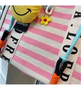 Detail of pink striped canvas tote bag with yellow smiley face and floral pendants