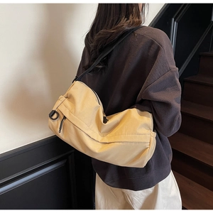 Detail of light khaki nylon crossbody bag showing the zipper and functional side D-ring