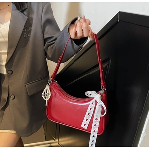 Dettaglio borsa a luna in pelle rossa con catena di perle e fiocco in pizzo