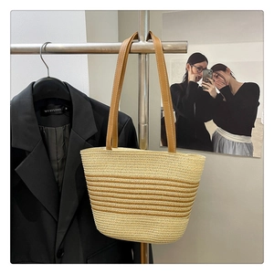 Detail of summer straw tote bag with striped weave patterns and brown leather straps