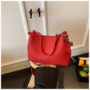 Dettaglio borsa a secchiello in pelle rossa testurizzata con fibbie metalliche argento