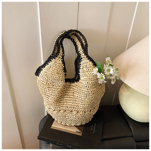 Detail of hand-woven straw tote bag with black contrast trim and daisy floral decor