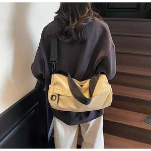 Practical large beige canvas crossbody bag shown worn on a shoulder in a stairwell setting