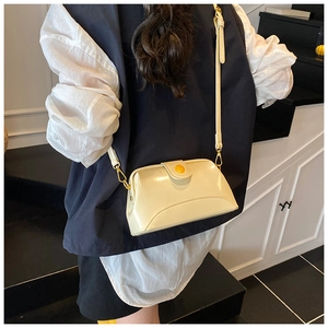 Détail d'un sac à bandoulière vintage crème porté par un mannequin sur un escalier